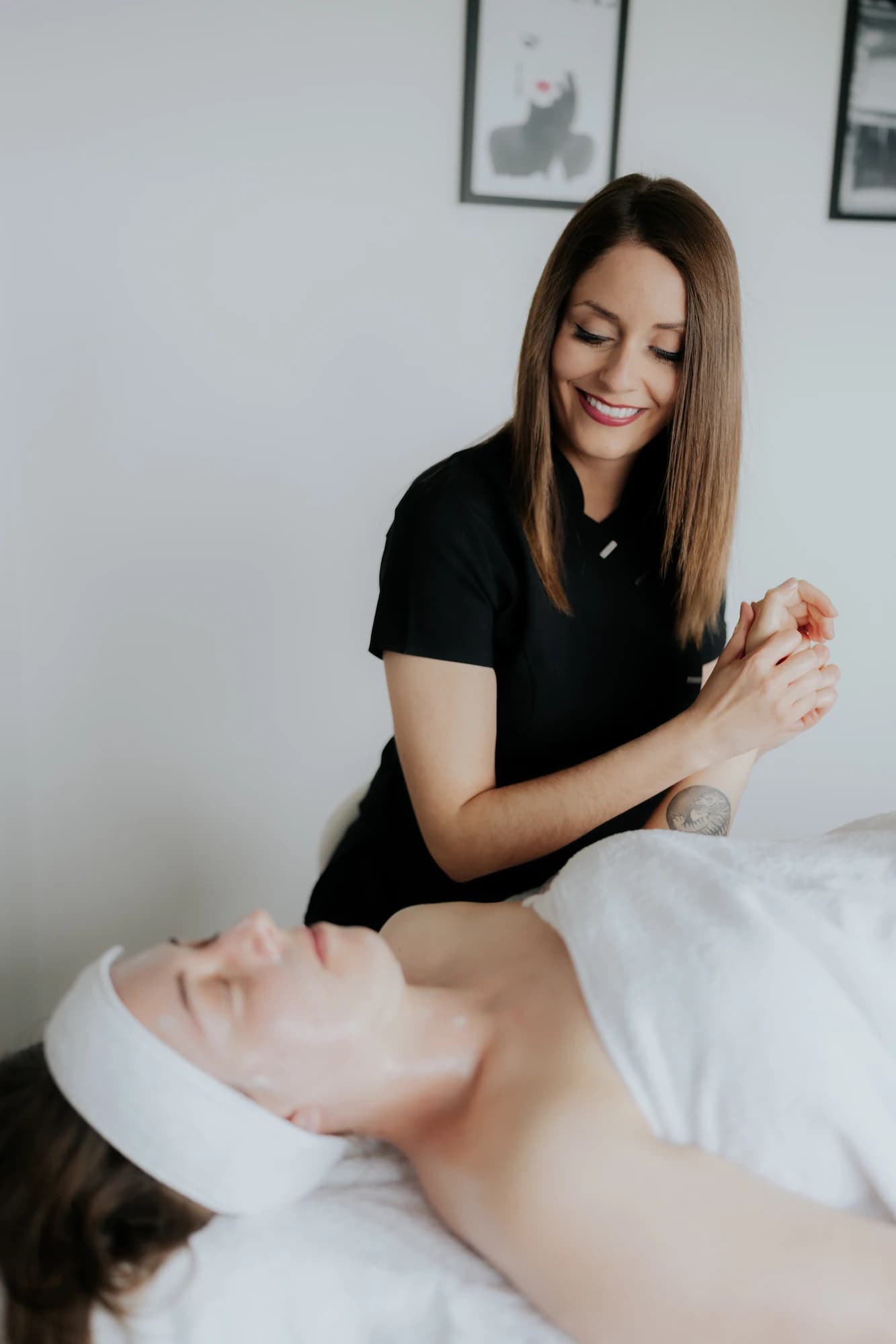 Esthéticienne en uniforme noir réalisant un soin du visage sur une cliente en institut de beauté – shooting photo Novacom Agency